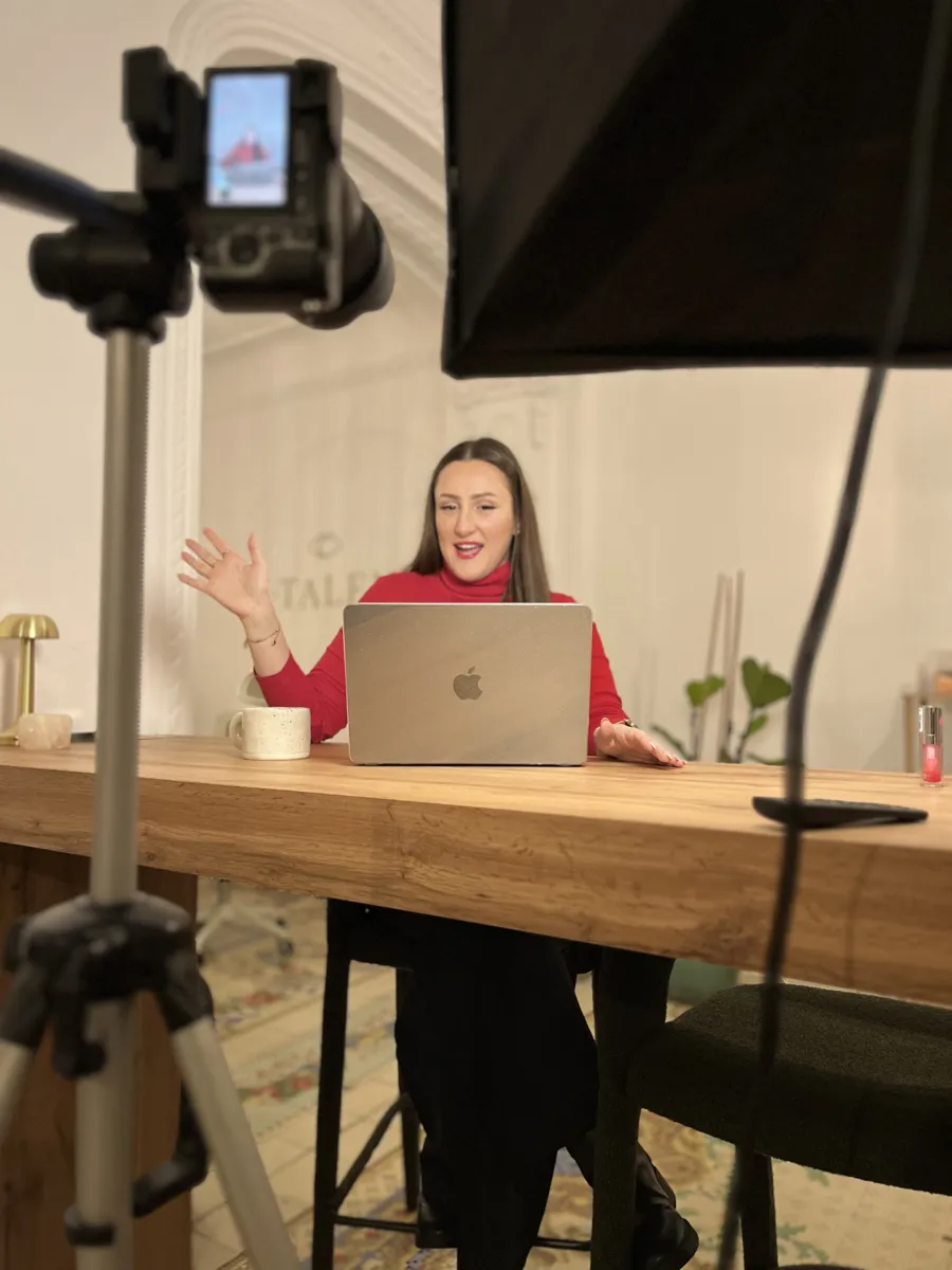 Elsinora filming a video at a wooden desk